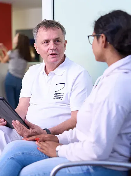 Arzt der Praxis für Radiologie und Nuklearmedizin in der Kaiser-Passage im Gespräch mit einer Patientin im Wartebereich.