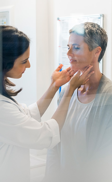 Ärztin tastet die Schilddrüse einer Patientin ab